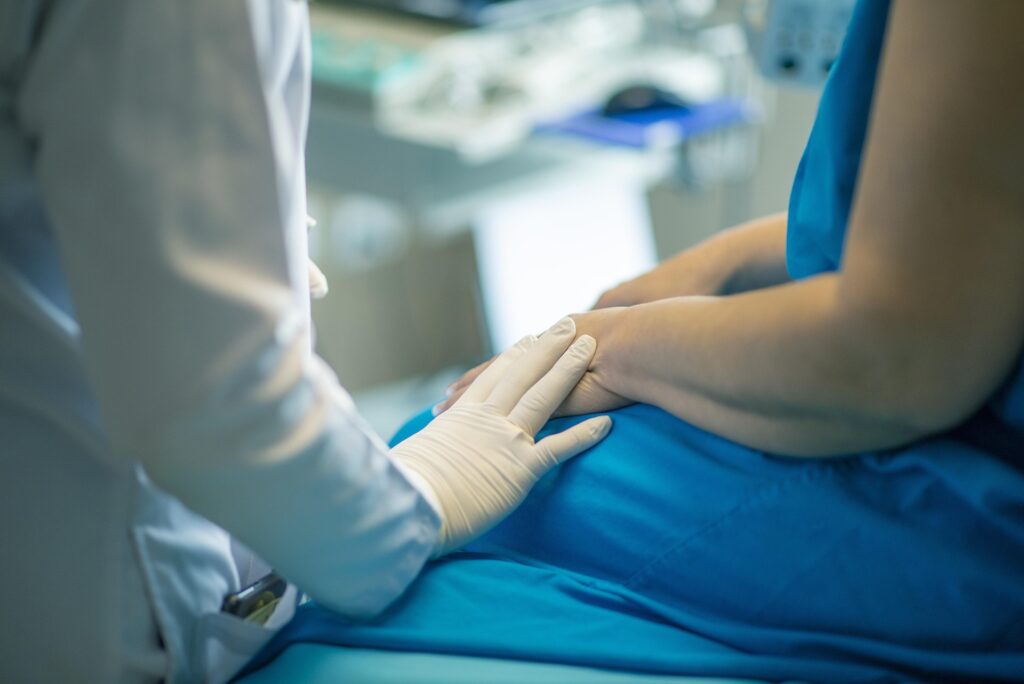 Paciente sentado en una camilla y el doctor tocando su mano
